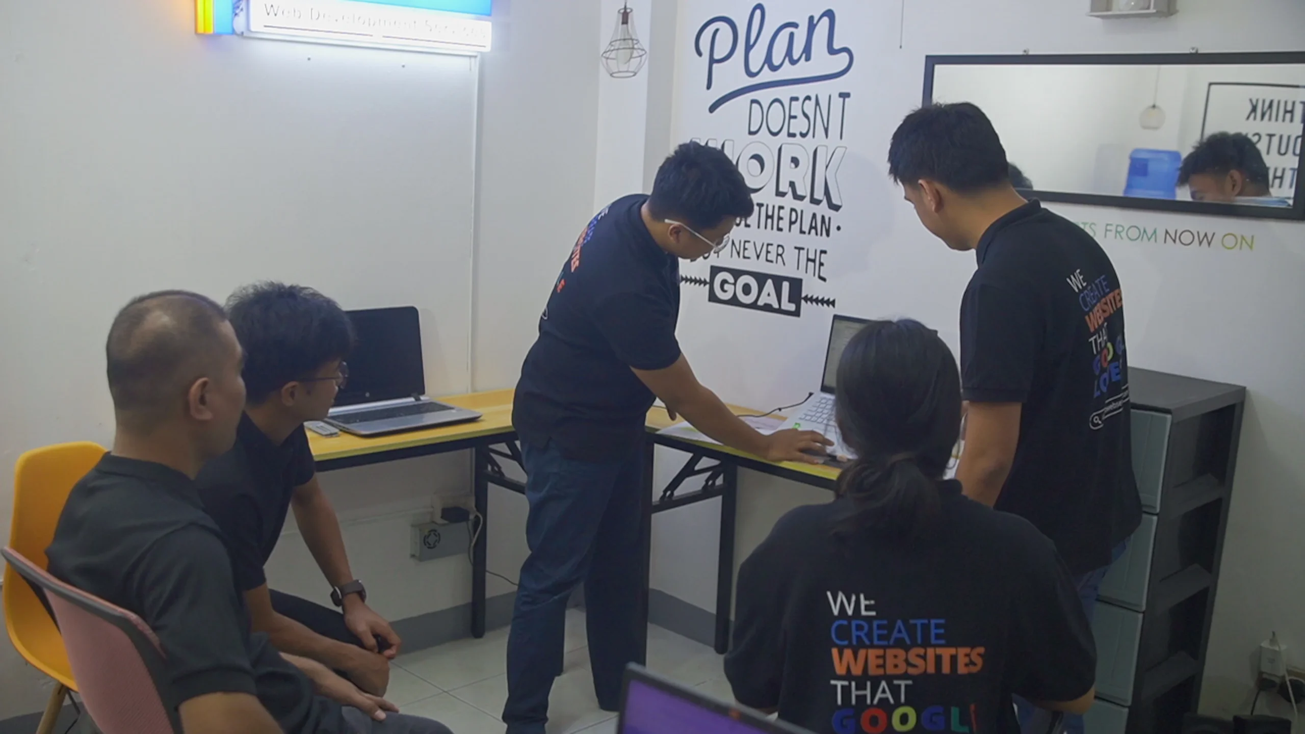A team member working on a website or digital project using a desktop computer in a shared workspace.