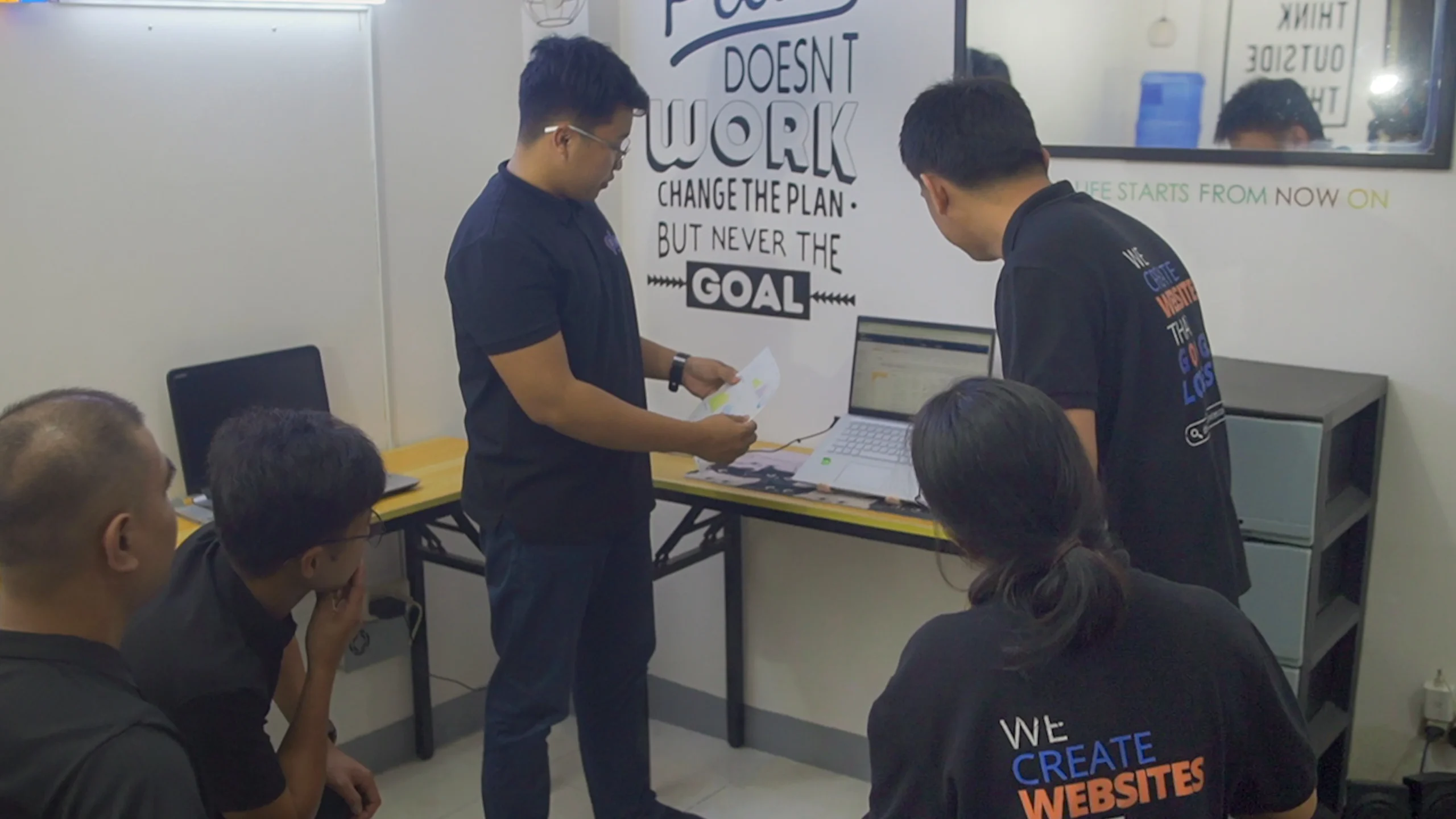 Team members collaborating around a whiteboard while discussing project goals and ideas.