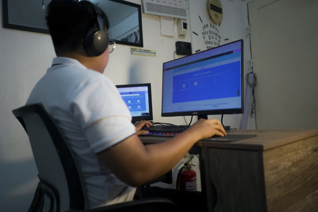 A team member using a desktop computer with headphones while contributing to a collaborative development project.